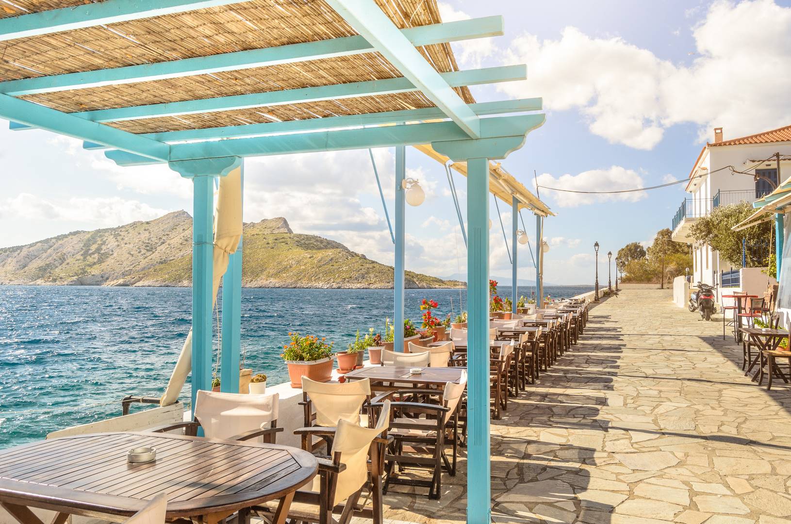 Summer photo with panoramic view from Aegina island in Greece. Beautiful place for making lunch on seafront with wooden roof of bar and restaurant. Magic moment during sunny day for chilling and relax