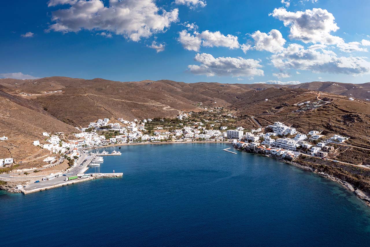 Greece, Kythnos island, Cyclades. Merihas port aerial drone view in the morning. Rocky landscape, Cycladic traditional architecture, sailboats at the marina. Calm sea, blue sky